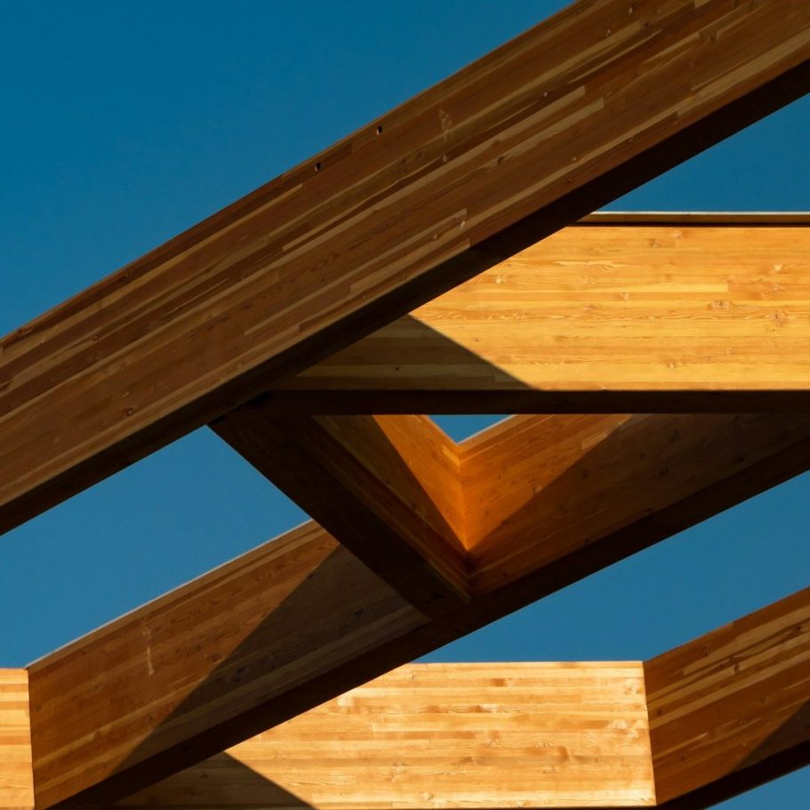 Holzbau mit sichtbaren Balken und blauem Himmel im Hintergrund.