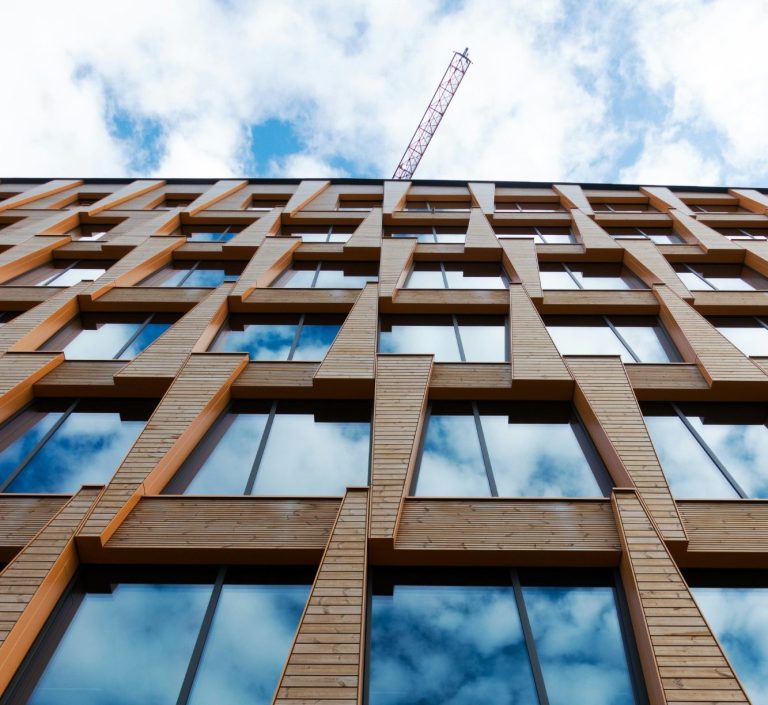 Moderne Gebäudeansicht mit Holz- und Glasfassade unter einem bewölkten Himmel.